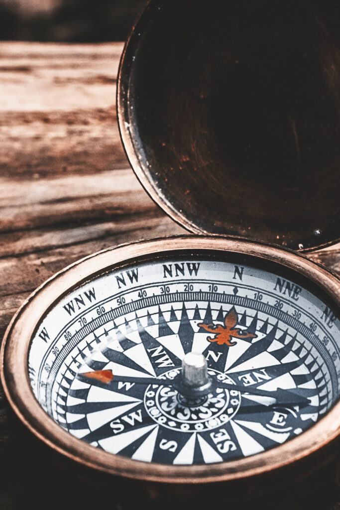 Nahaufnahme eines alten Kompasses aus Metall auf Holzuntergrund – Symbol für Orientierung, Werte und innere Ausrichtung.