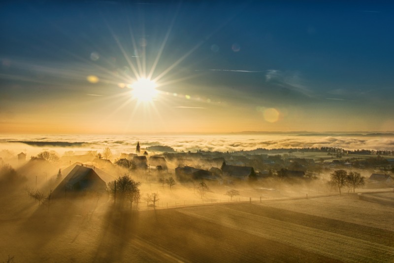 Sonnenaufgang über nebliger Landschaft als Symbol für den Übergang zwischen Idee und Umsetzung in Organisationen